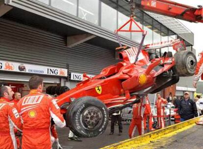 Los operarios de Ferrari descargan el coche accidentado de Raikkonen, tras la carrera de ayer.