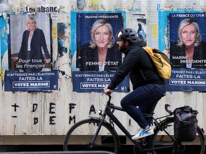 Un hombre pedalea delante de varios carteles electorales de Marine Le Pen, este lunes en París.