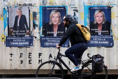 Un hombre pedalea delante de varios carteles electorales de Marine Le Pen, este lunes en París.