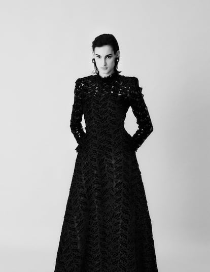 Nine d’Urso in a re-creation of a Balenciaga evening gown from 1938. The two-piece gown has a historicist cut and is made of hand-embroidered openwork silk velvet. The dress is superimposed on a black silk bodice, which allows a partial view of the body. 