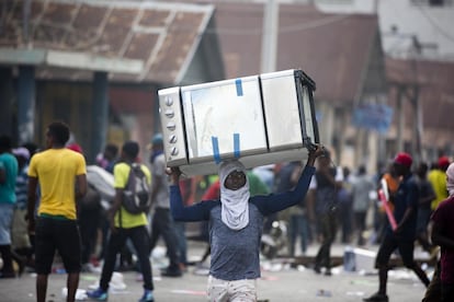 Na capital do país, escolas e bancos ainda estão fechados, além de empresas e postos de combustíveis, muitos dos quais foram saqueados nos dias de hoje, uma situação que deixou milhões em perdas no Haiti, o país mais pobre das Américas. Um homem carrega uma cozinha após o saque de uma loja, em 12 de fevereiro de 2019.