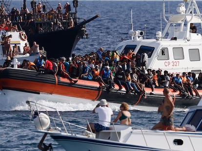 Un barco con migrantes rodeado de yates con turistas, este lunes en Lampedusa.