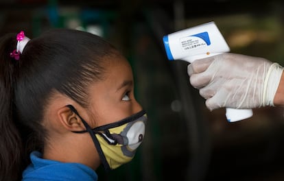 Un sanitario toma la temperatura a una niña en la Ciudad de México.