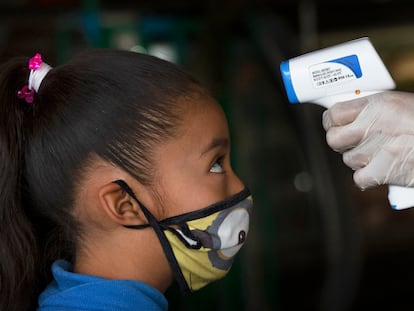 Un sanitario toma la temperatura a una niña en la Ciudad de México.