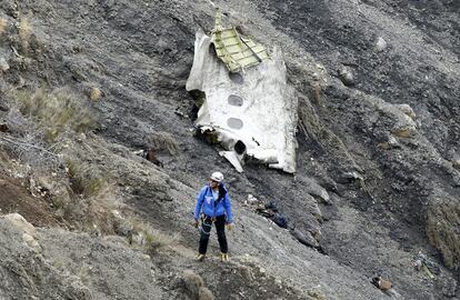 Un miembro de los servicios de rescate camina al lado del mayor resto de fuselaje del avin siniestrado, en el que se aprecian tres ventanillas, entre millones de fragmentos del aparato esparcidos por una amplia rea de alta monta?a en los Alpes franceses.