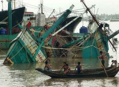 Un bote pasa delante de barcos de pesca hundidos por el ciclón en el puerto de Yangon.