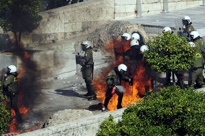Policías antidisturbios tratan de apagar el fuego provocado por un cóctel molotov lanzado por los manifestantes cerca del Parlamento griego.