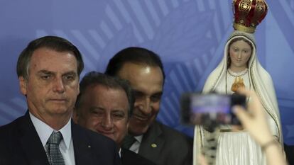 Bolsonaro posa para una foto con una imagen de la virgen de Fátima al fondo.