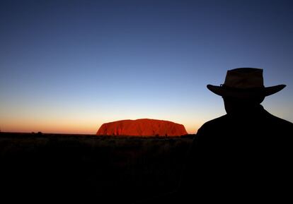 Un hombre mira el monte Uluru al atardecer, en Australia.