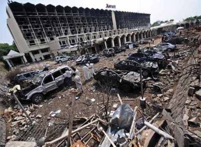 Un grupo de investigadores revisa los coches destruidos por el atentado en el aparcamiento del hotel Marriott en Islamabad.