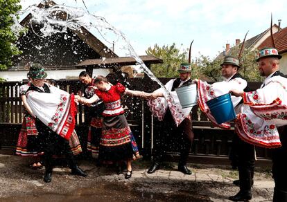 Un grupo de jóvenes lanza cubos de agua a una chica, vestida con un traje tradicional, durante la celebración del Lunes de Pascua, en Cikó, Hungría. Según la tradición húngara, el Lunes de Pascua los hombres jóvenes mojan con agua a las mujeres jóvenes y, a cambio, estas les regalan huevos de pascua.