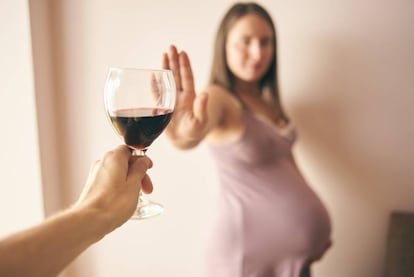 Una mujer embarazada rechaza una copa de vino.