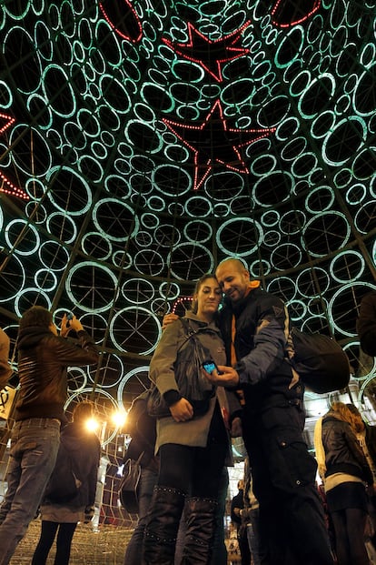 Una pareja se hace una foto desde dentro del pino lumínico situado en la Puerta del Sol.