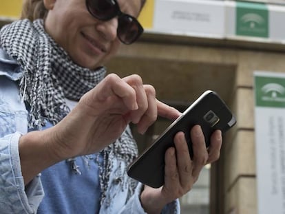 Una mujer usa un móvil en la puerta de una oficina de empleo en Sevilla.
 