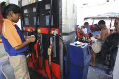La trabajadora de una gasolinera cuenta dinero junto a un surtidor en una gasolinera en Quezon (Filipinas). EFE/Archivo