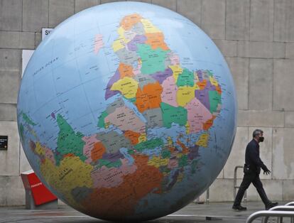 Un hombre pasa por delante de un globo terráqueo frente a la London School of Economics en Londres (Inglaterra). Las autoridades sanitarias del Reino Unido han alertado este miércoles de que el país ha registrado una nueva cifra récord de fallecidos a causa de la covid-19 tras sumar 1.820 muertos en el último día.