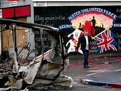 Un hombre pasa ante los restos de un autobús incendiado esta noche en Belfast.