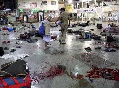 Un policía ayuda a un hombre a cruzar la estación de ferrocarril de Bombay, donde se produjo uno de los atentados.
