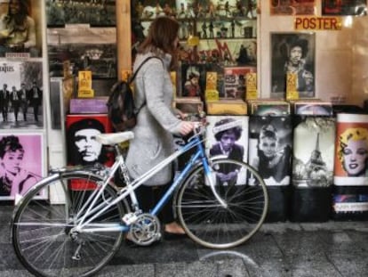 Una chica ojea discos de vinilo junto a su vieja bicicleta. 