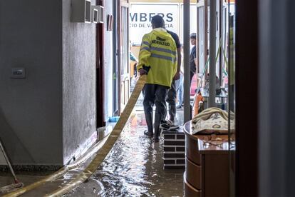 Un bombero saca una manguera del interior de una casa inundada en Valencia.