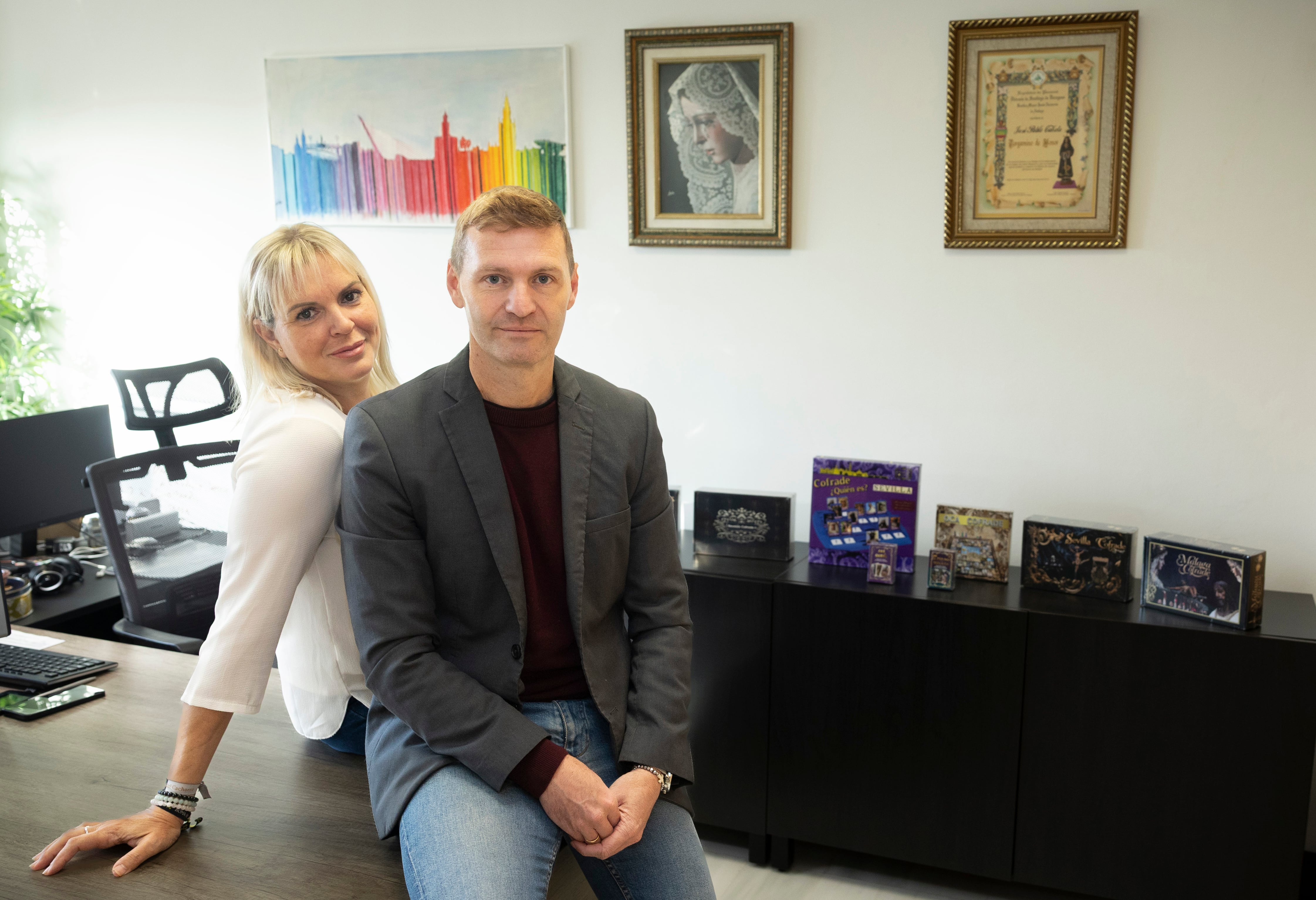 Rosa Marín y Pablo Cañete, creadores de juegos de mesa cofrades, que están exhibidos detrás.
