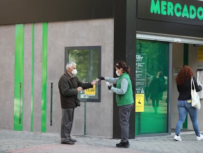 Una trabajadora de un supermercado madrileño reparte guantes a los clientes.