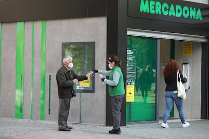 Una trabajadora de un supermercado madrileño reparte guantes a los clientes.