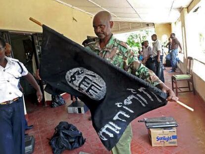 Un polic&iacute;a keniano sostiene una bandera isl&aacute;mista incautada en las recientes redadas en mesquitas en Mombasa.