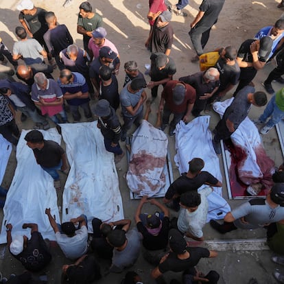 Palestinians mourn over the bodies of people killed either by Israeli military strikes or while trying to reach aid trucks, outside Shifa Hospital, in Gaza City, Thursday, Aug. 21, 2025. (AP Photo/Jehad Alshrafi)