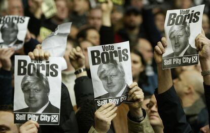 Torcedores do Manchester United provocam um grupo de pessoas de Liverpool com os cartazes de Boris Johnson durante uma partida de futebol no estádio Anfield em 15 de janeiro de 2005. Em outubro do ano anterior, Johnson tinha visitado Liverpool para se desculpar formalmente após a revista 'The Spectator' publicar um artigo em que descreveu a cidade como "viciada em pesar" desde o assassinato do refém Kenneth Bigley.