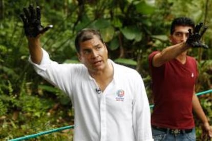 El presidente de Ecuador Rafael Correa (i) muestra su mano manchada de crudo de un reservorio antiguo de desechos petroleros en el pozo Aguarico 4 en la Amazonía (Ecuador), para demostrar la "mano negra de Chevron", compañía condenada a una millonaria indemnización por daños ambientales en la selva.