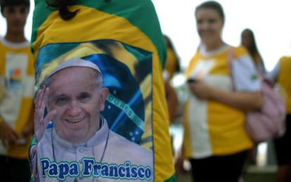 A young pilgrim wrapped in a Brazilian flag with an image of Pope Francis speaks with mates in Rio de Janeiro.