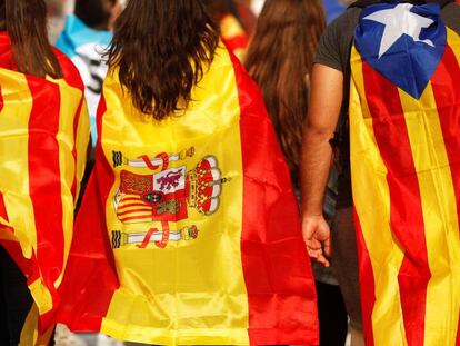 Tres jóvenes acuden a una manifestación en Barcelona con una senyera, una bandera de España y una estelada.