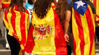 Tres jóvenes acuden a una manifestación en Barcelona con una senyera, una bandera de España y una estelada.