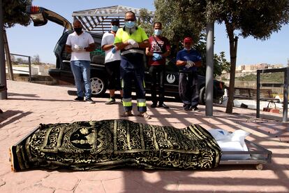 Familiares y trabajadores del cementerio de Melilla rezan ante el cadáver de Kozal Ahmad.