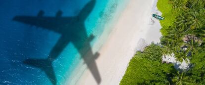 Un avión sobrevuela una playa.