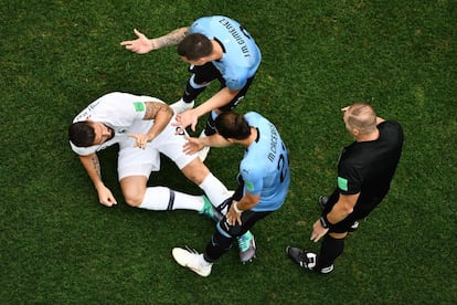 El defensa uruguayo Jose Giménez comprueba cómo está el francés Olivier Giroud.