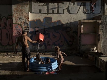 Homem banha crianças em uma favela do Rio de Janeiro.