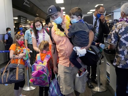 Hawaii resident Ryan Sidlow carries his son as their family boards a United Airlines flight to Hawaii at San Francisco International Airport in October 2020.