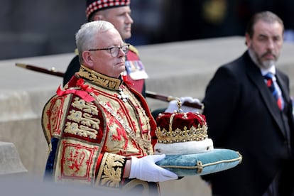 Joseph John Morrow, Lord Lyon King of Arms —la máxima autoridad heráldica escocesa—, sostiene la Corona de Escocia, hecha para el rey Jacobo V de Escocia en 1540 y que solía llevar María de Estuardo en 1543.