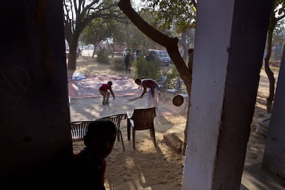 Estudiantes barren la alfombra antes de tomar el tratamiento que se reparte en la escuela.