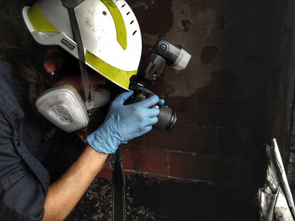Una agente de la unidad de inspección ocular de los Mossos d'Esquadra toma imágenes del lugar de un incendio.