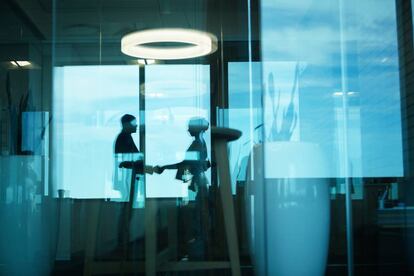 Dos empresarios dándose la mano en una oficina. Getty Images