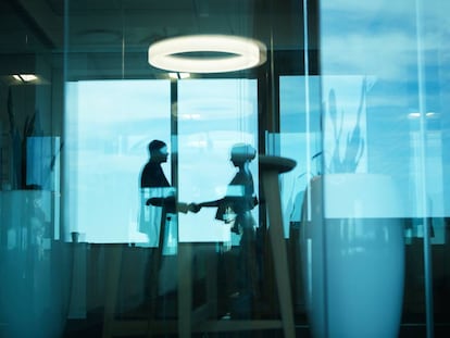 Dos empresarios dándose la mano en una oficina. Getty Images