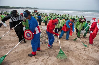 Trabajadores vestidos de súperhéroes barren la basura de la playa de Kuta, en Bali (Indonesia).