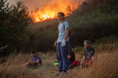 Vecinos de Bendollo observan la evolución del incendio que asola sus casas en la sierra de O Courel, este lunes. 