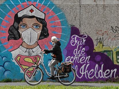 Una mujer monta en bicicleta, en Hamm, al oeste de Alemania, junto a un mural de una enfermera en el que se lee: "Para los verdaderos héroes".