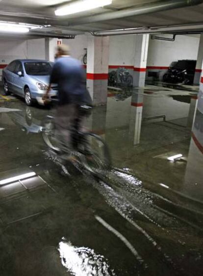 Un hombre cruza un garaje lleno de agua en Valdemoro.