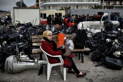 Una mujer espera entre motores de las embarcaciones con las que los inmigrantes llegan a la costa tras cruzar el mar Egeo, en Mitilene, Grecia.