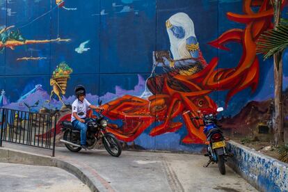 Un hombre baja en moto por una de las rampas de la Comuna 13. A su lado, en la pared, uno de los grafittis que adornan esta barriada. 